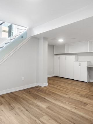 an empty room with a desk, computer, and stairs