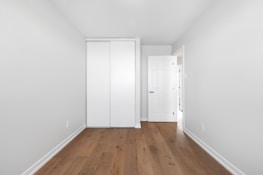 an empty room with a white door and wooden floor