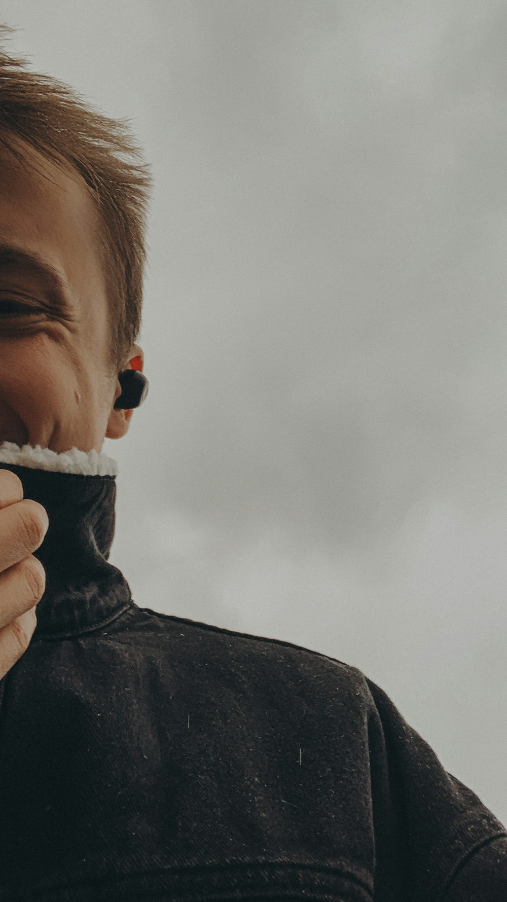 a man holding something in his mouth while wearing a black jacket