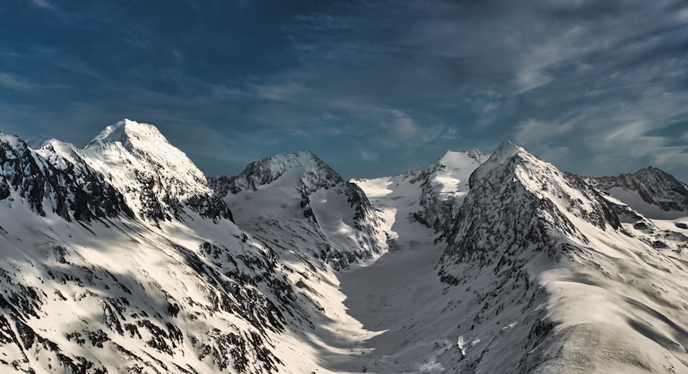 Une chaîne de montagnes enneigée sous un ciel nuageux