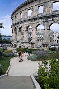 a group of people walking down a walkway next to an old building