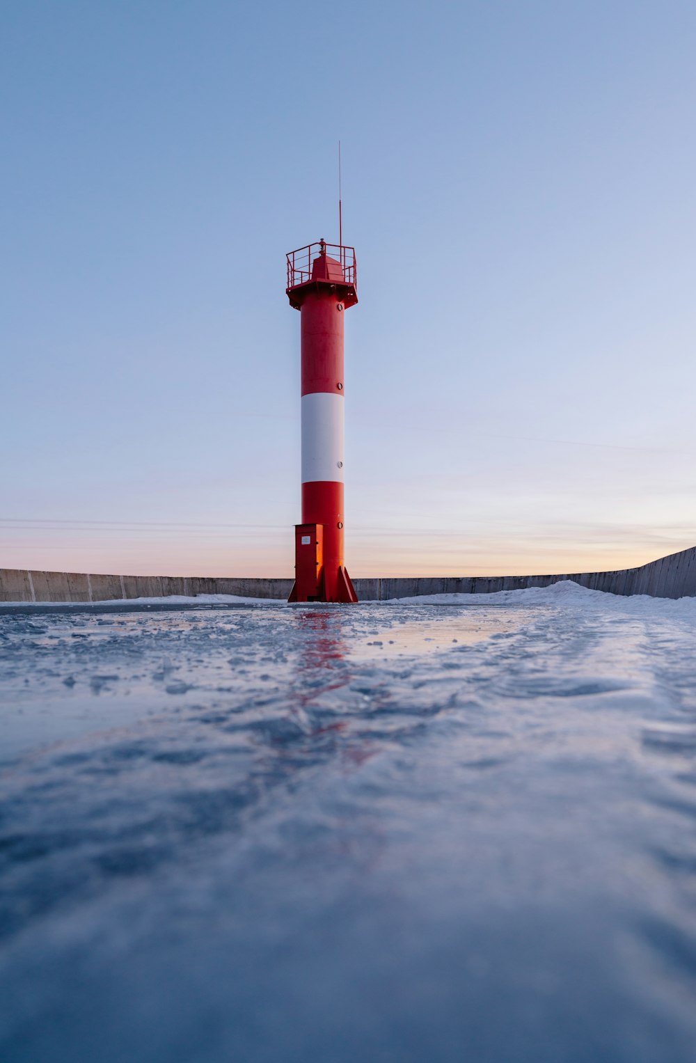 a red and white lighthouse in the middle of the ocean