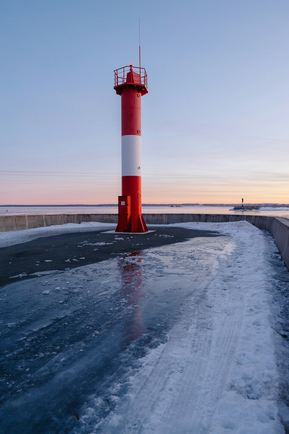 a red and white lighthouse sitting on top of a frozen lake