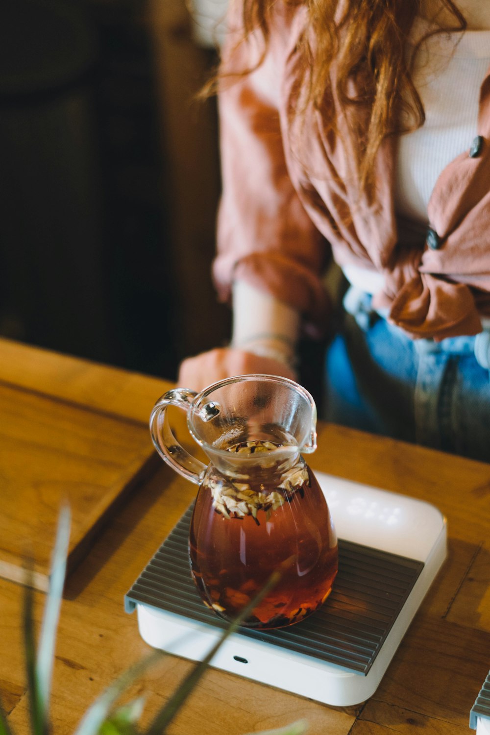 a woman sitting at a table with a pitcher of tea