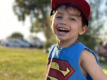 A smiling boy wearing a cool, durable outfit outdoors on a sunny day.