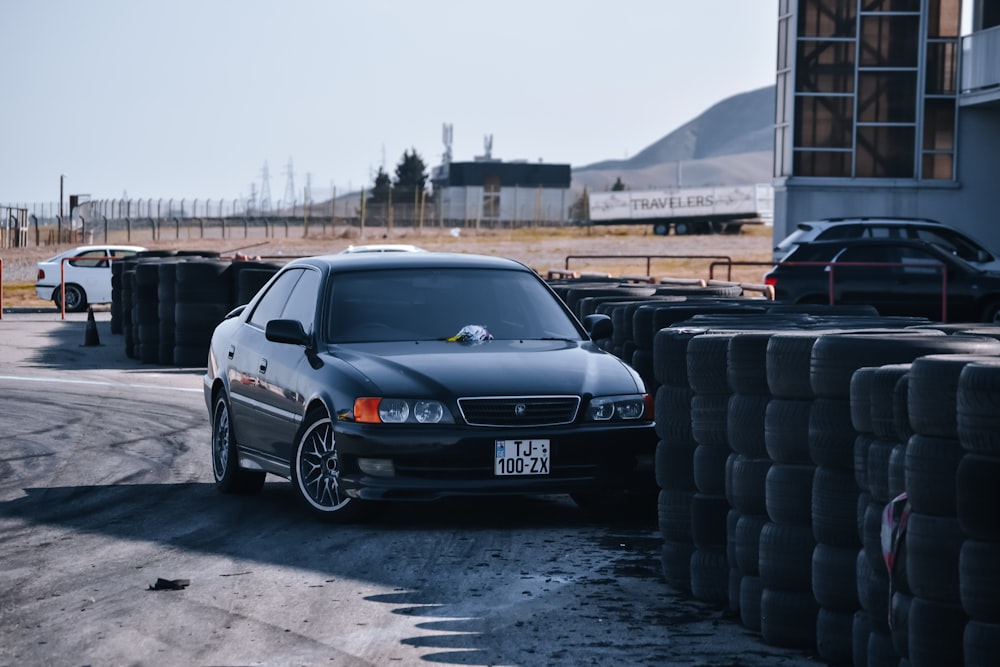 a black car parked next to a pile of tires