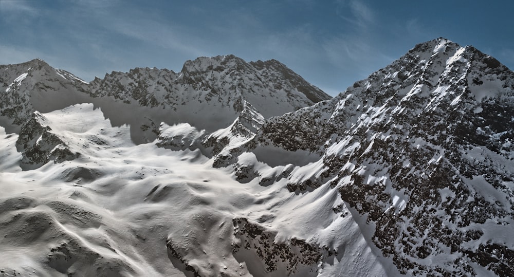 a mountain range covered in snow under a blue sky