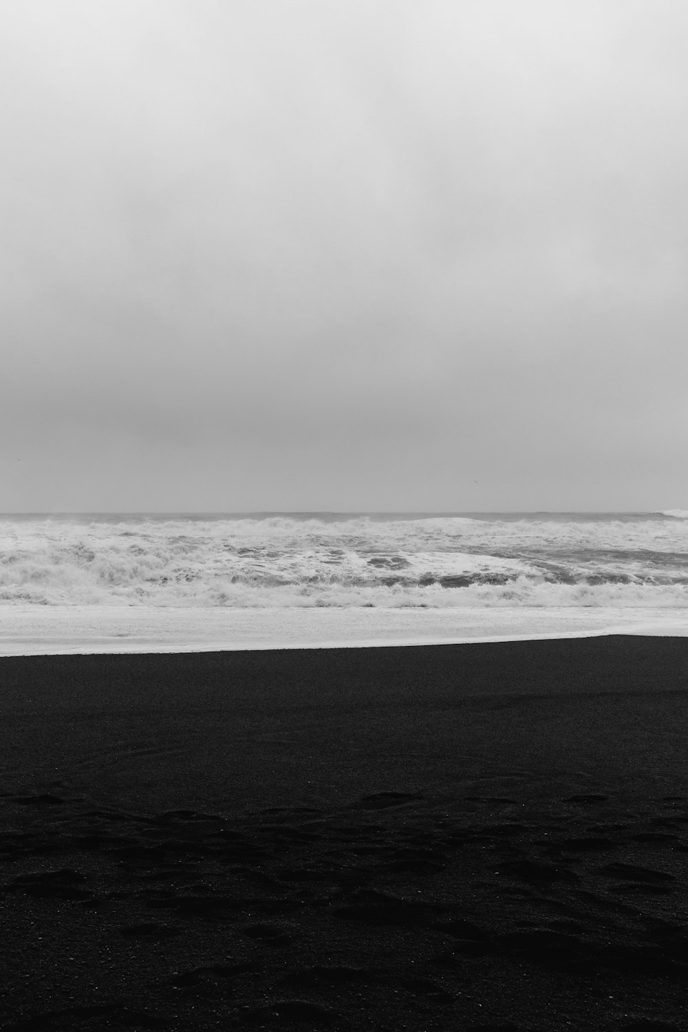 a black and white photo of a person carrying a surfboard