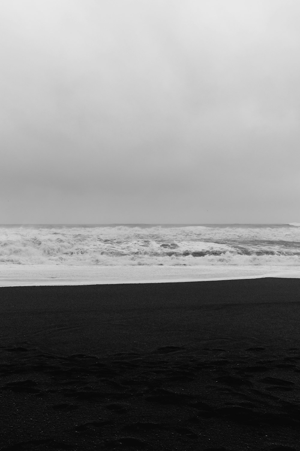 una foto in bianco e nero di una persona che trasporta una tavola da surf