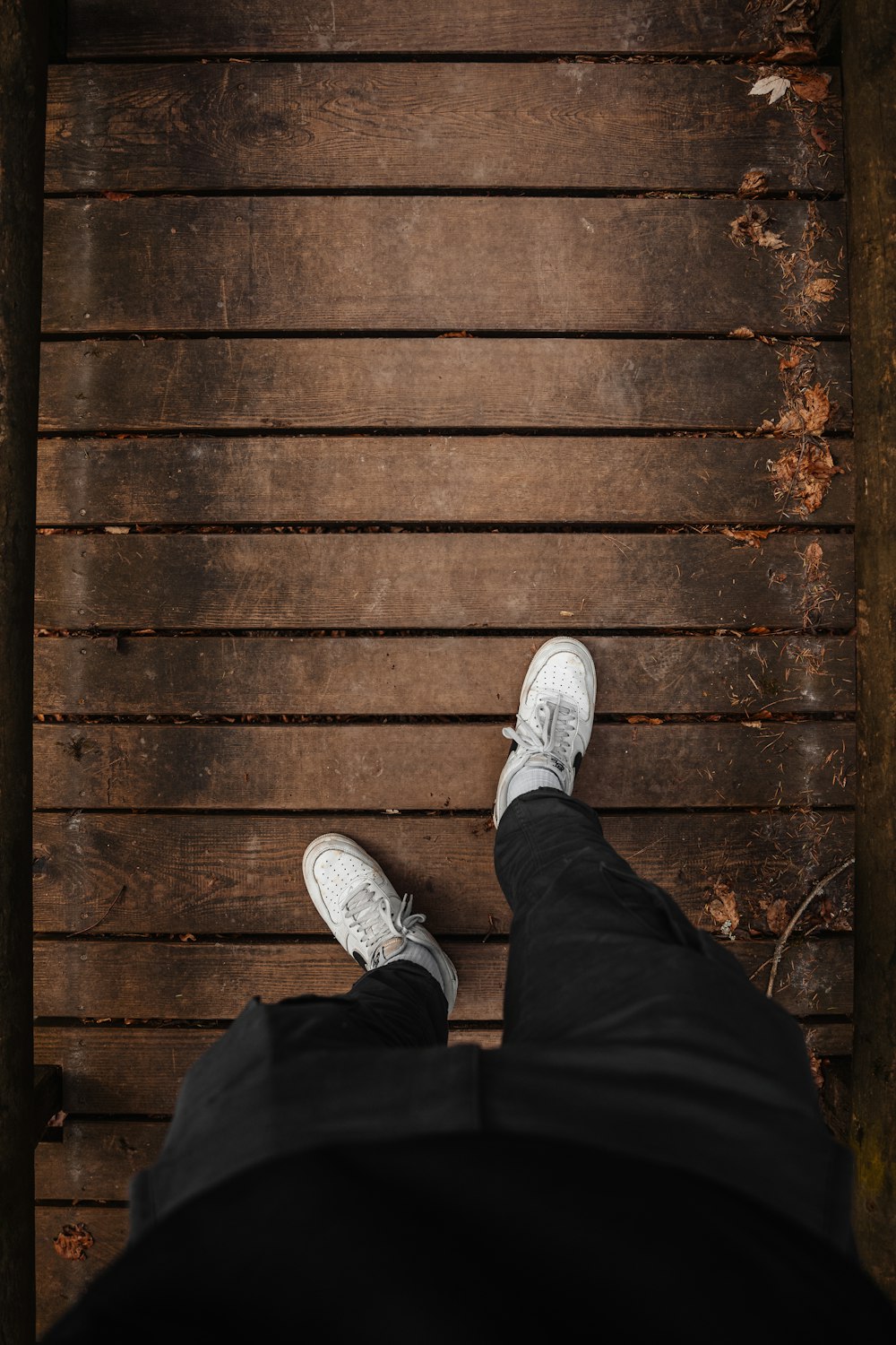 a person wearing white shoes standing on a wooden floor