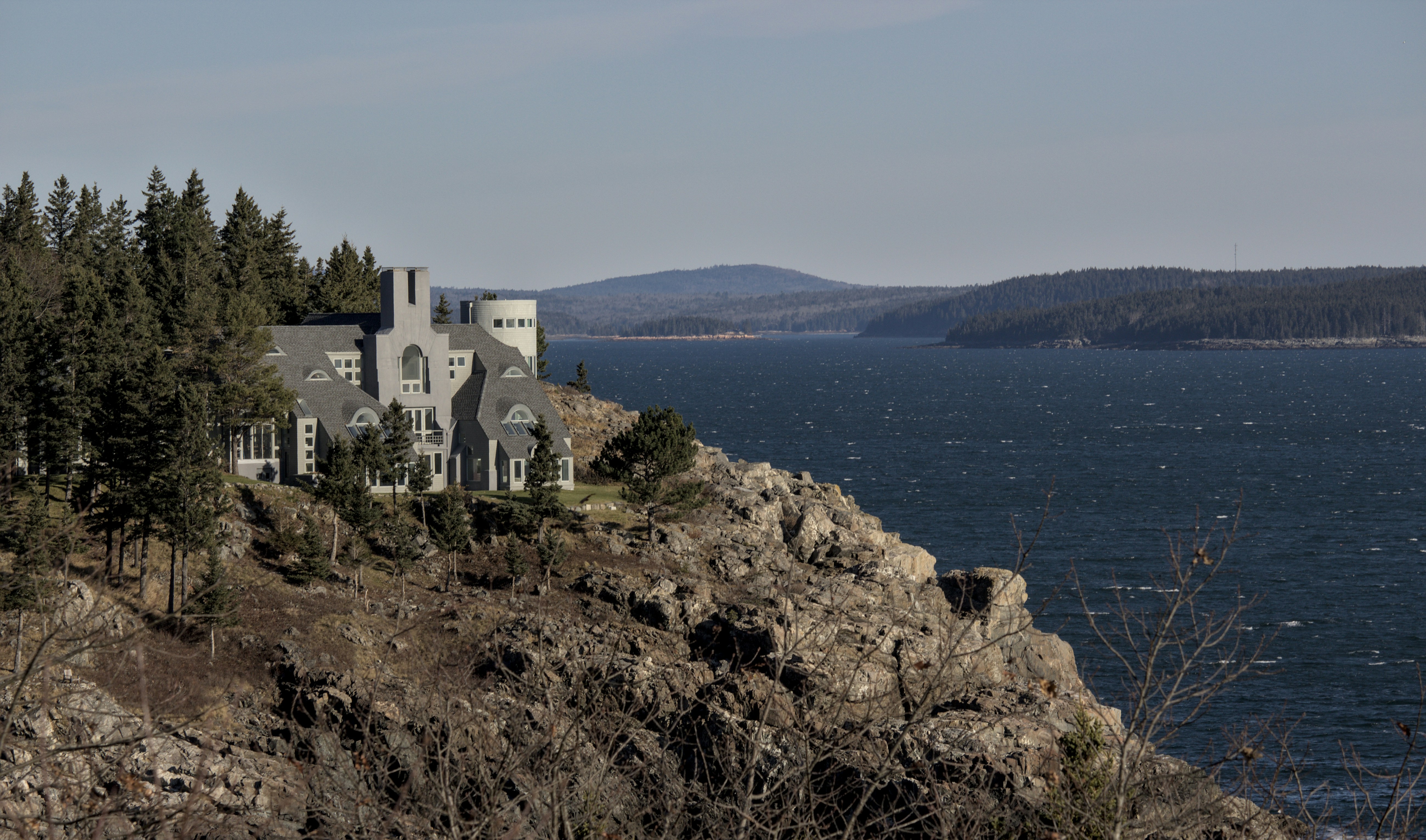 a house sitting on top of a cliff next to a body of water