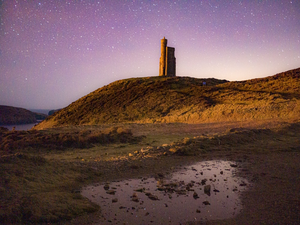 a small tower on a hill with stars in the sky