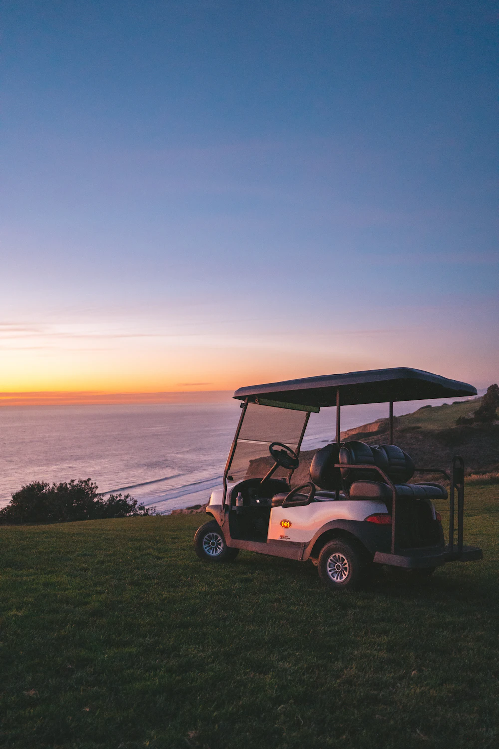 Golf cart by the ocean at sunset