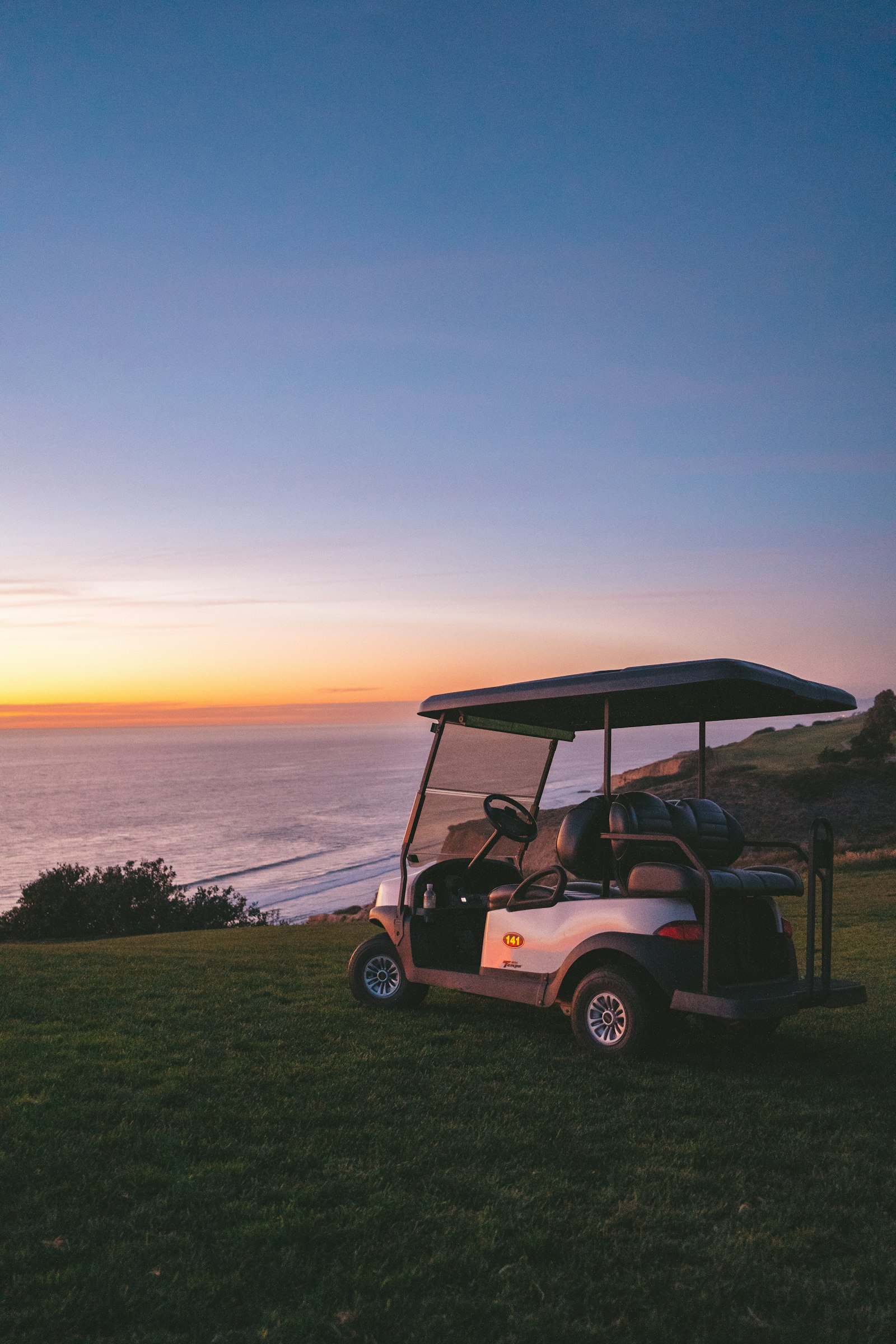 A golf cart parked on a coastal overlook at sunset