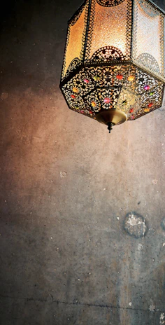 A glowing Moroccan lantern casting intricate shadows on a textured clay wall.