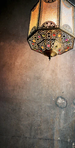 Close-up of intricate brass lanterns casting warm, patterned shadows on a terracotta wall.