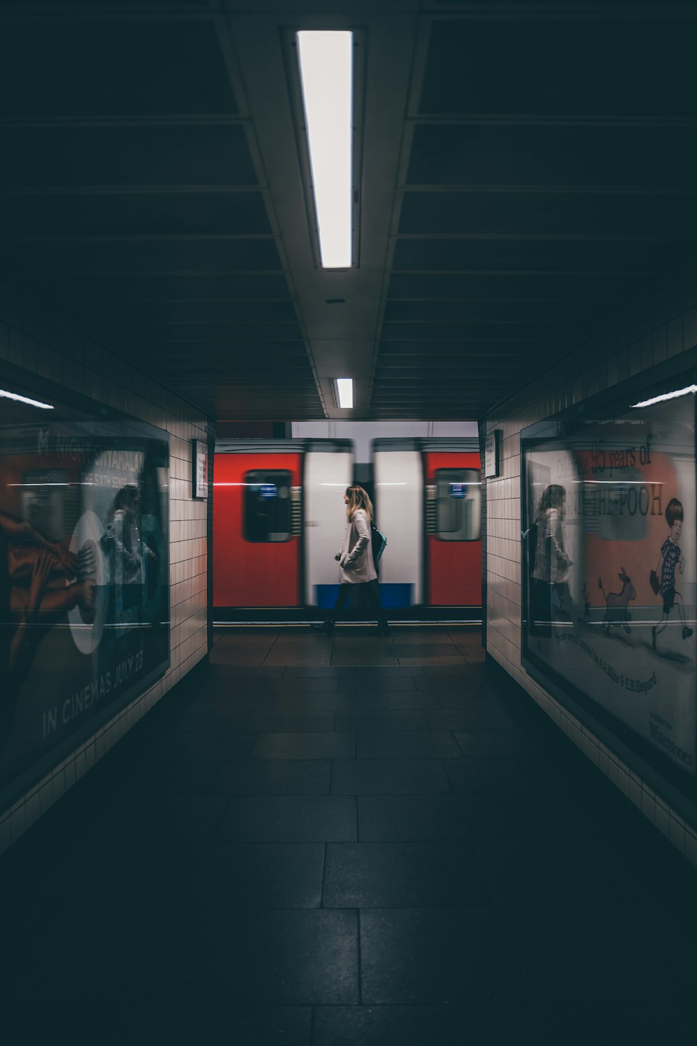 a subway station with a woman walking down the platform