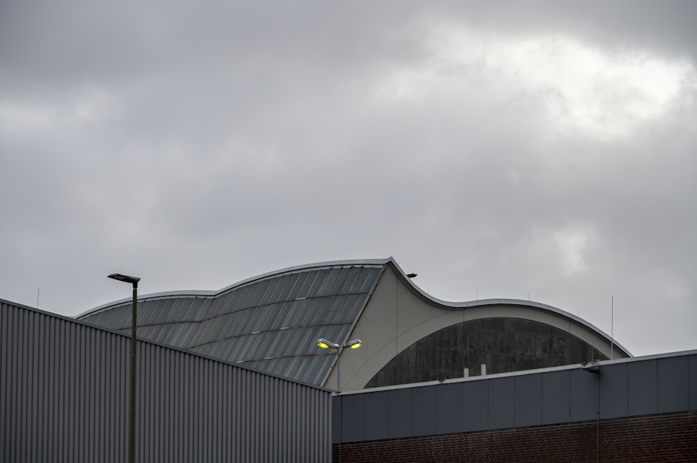 a building with a curved roof on a cloudy day
