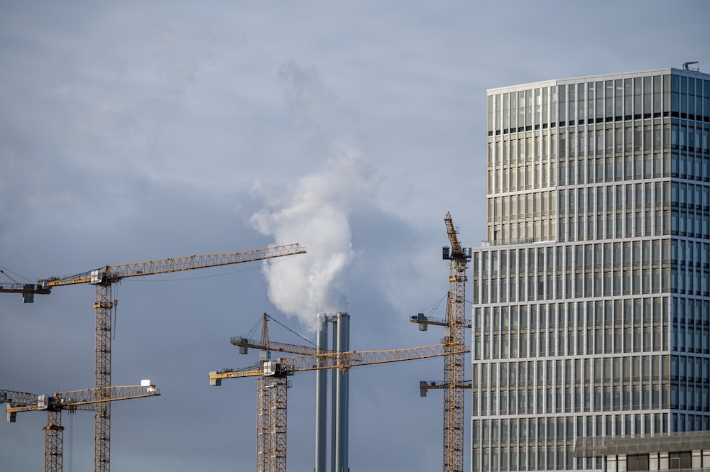 a group of cranes standing in front of a tall building