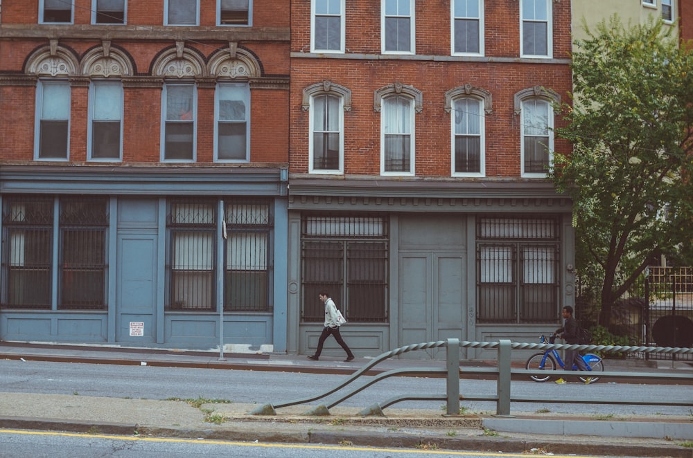 a man walking down a street past a tall building