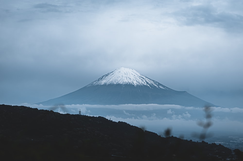 a mountain covered in clouds and snow on a cloudy day