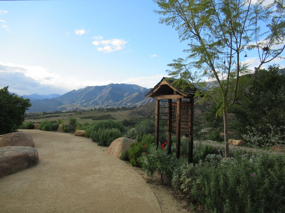 a small wooden structure in the middle of a dirt road