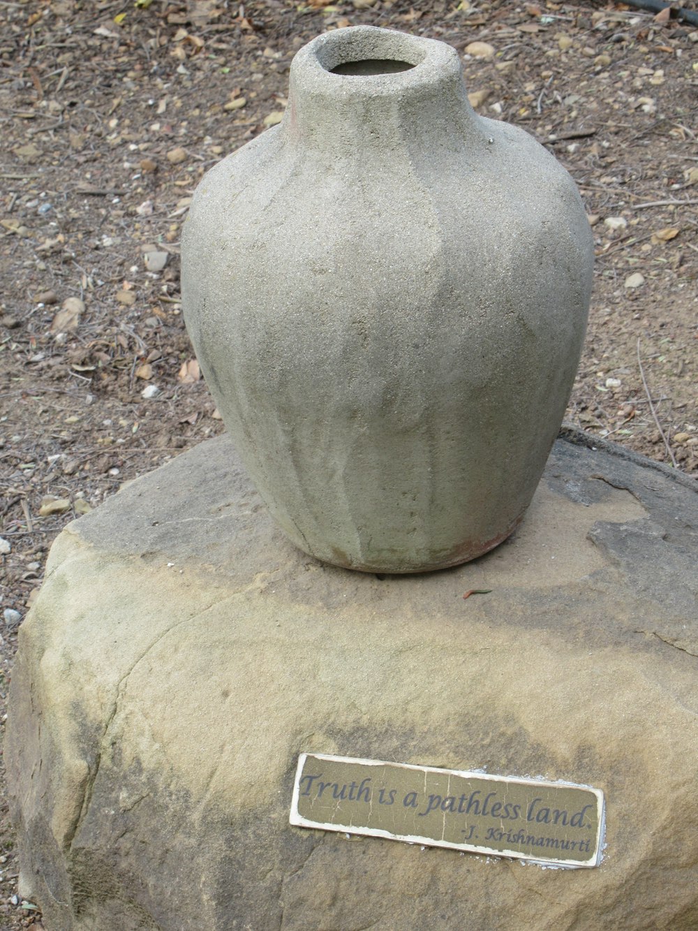 Un jarrón de piedra sentado encima de una roca