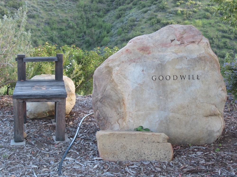 a wooden chair sitting next to a large rock