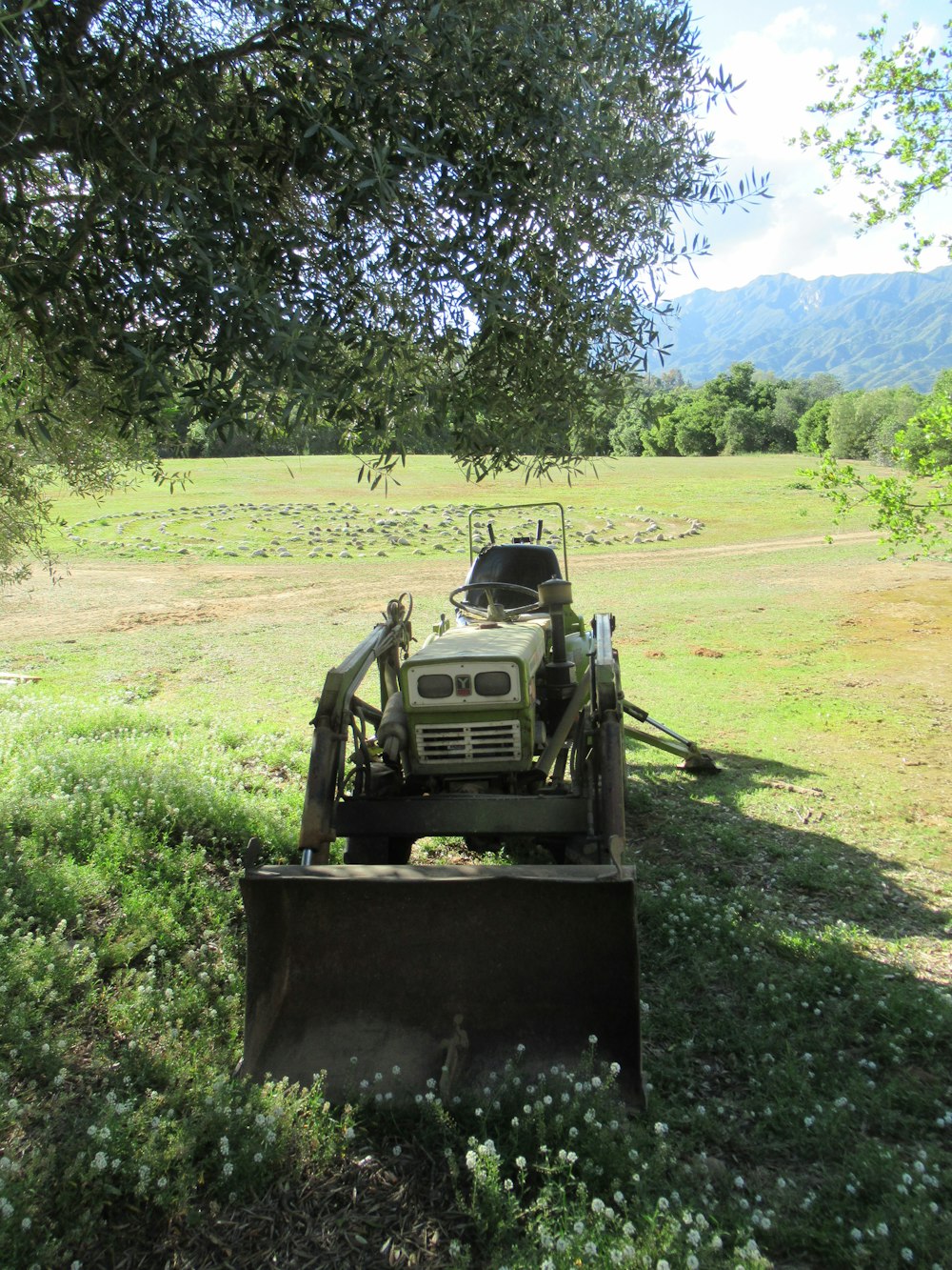 a tractor parked under a tree in a field