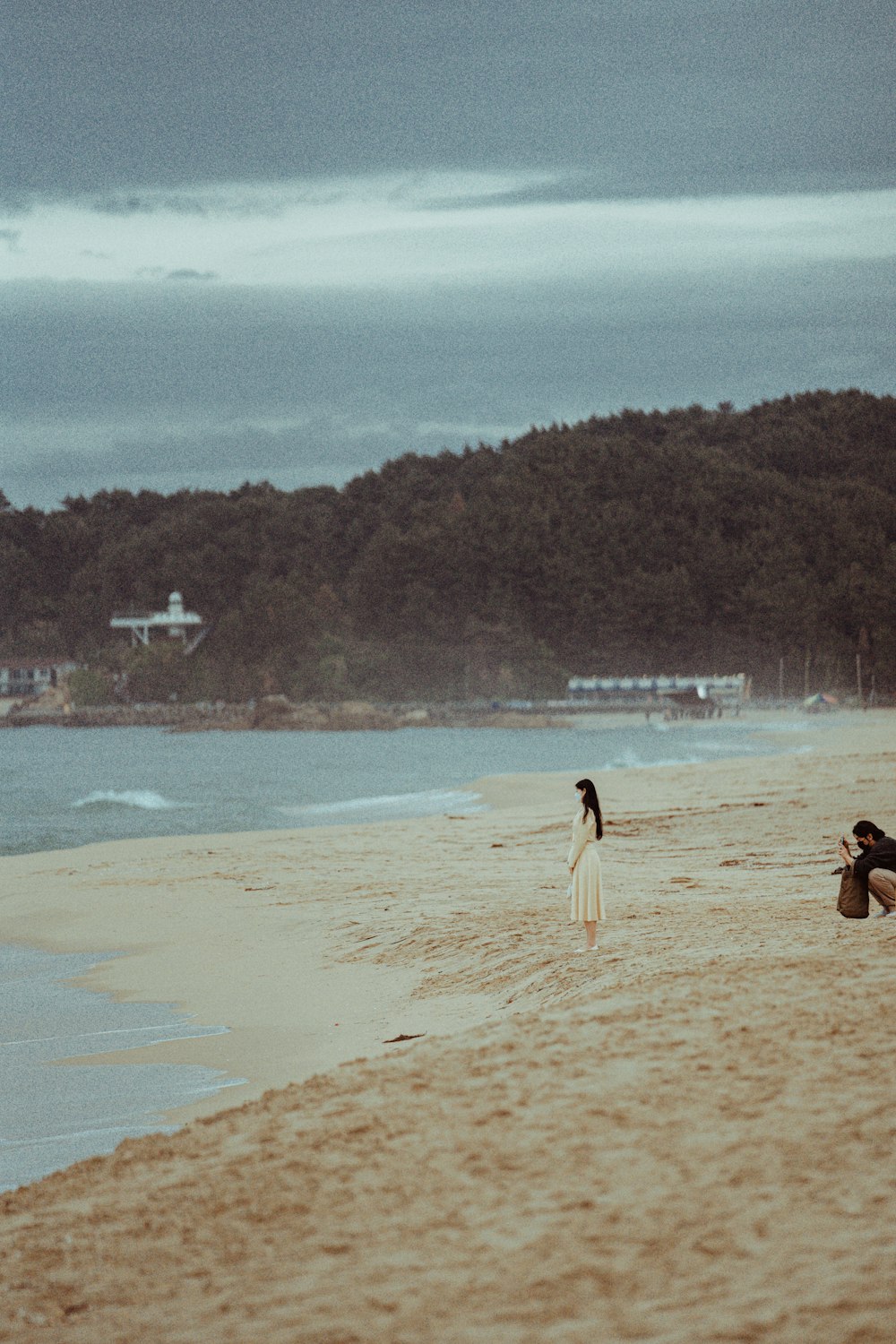 a person kneeling down on a beach with a surfboard