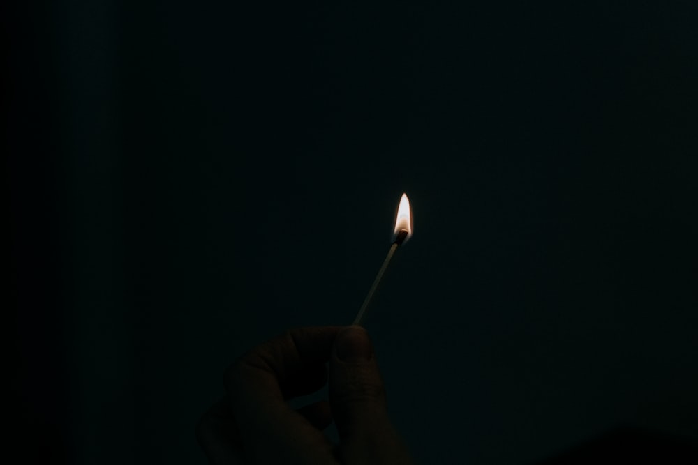 a person holding a lit matchstick in their hand