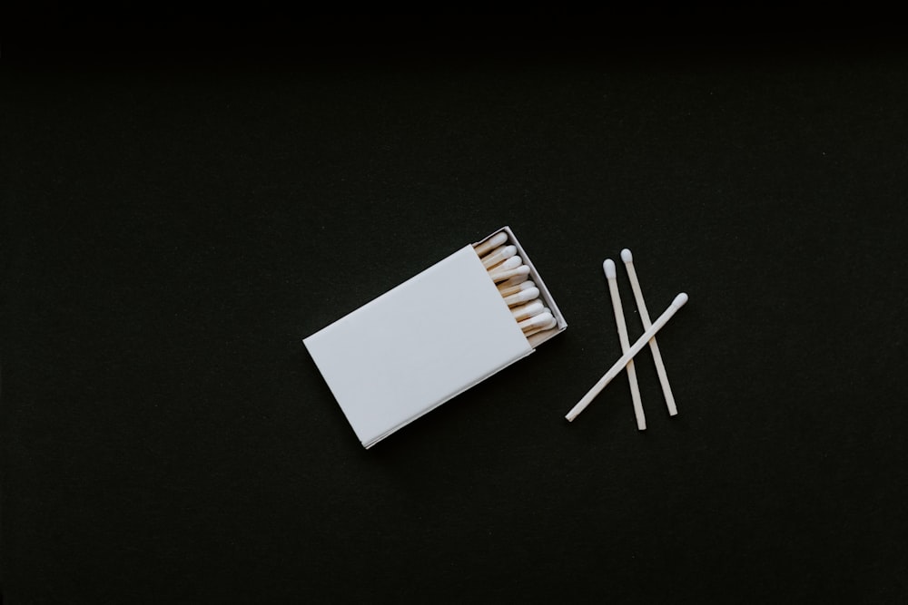 a box of matches and two sticks on a black surface