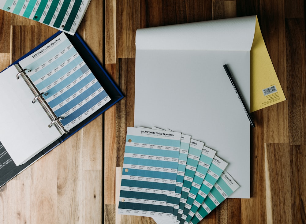 a binder, pen, paper, and folders on a wooden floor