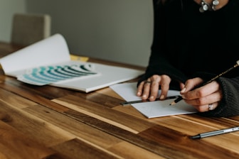 a woman sitting at a table with a pen and paper