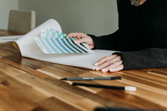 An architect and client reviewing floorplans over a wooden table with color swatches.