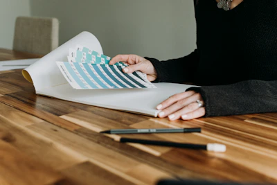 An architect and client reviewing floorplans over a wooden table with color swatches.