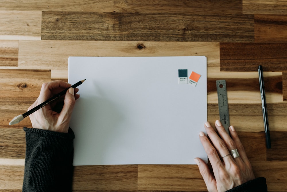 a person holding a pencil and drawing on a piece of paper