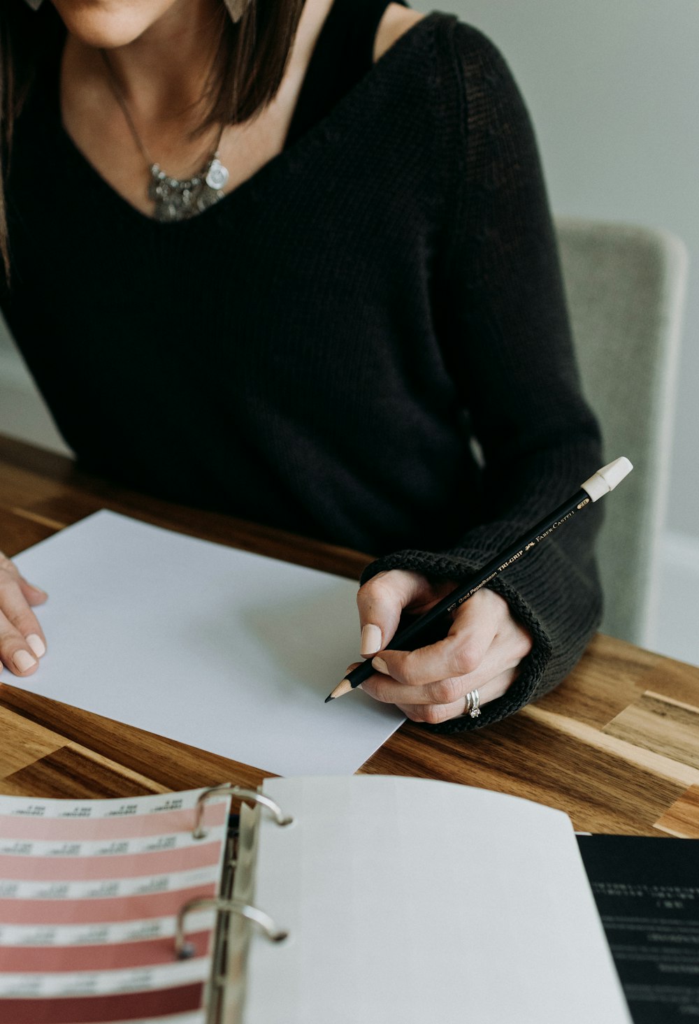 a woman sitting at a table writing on a piece of paper