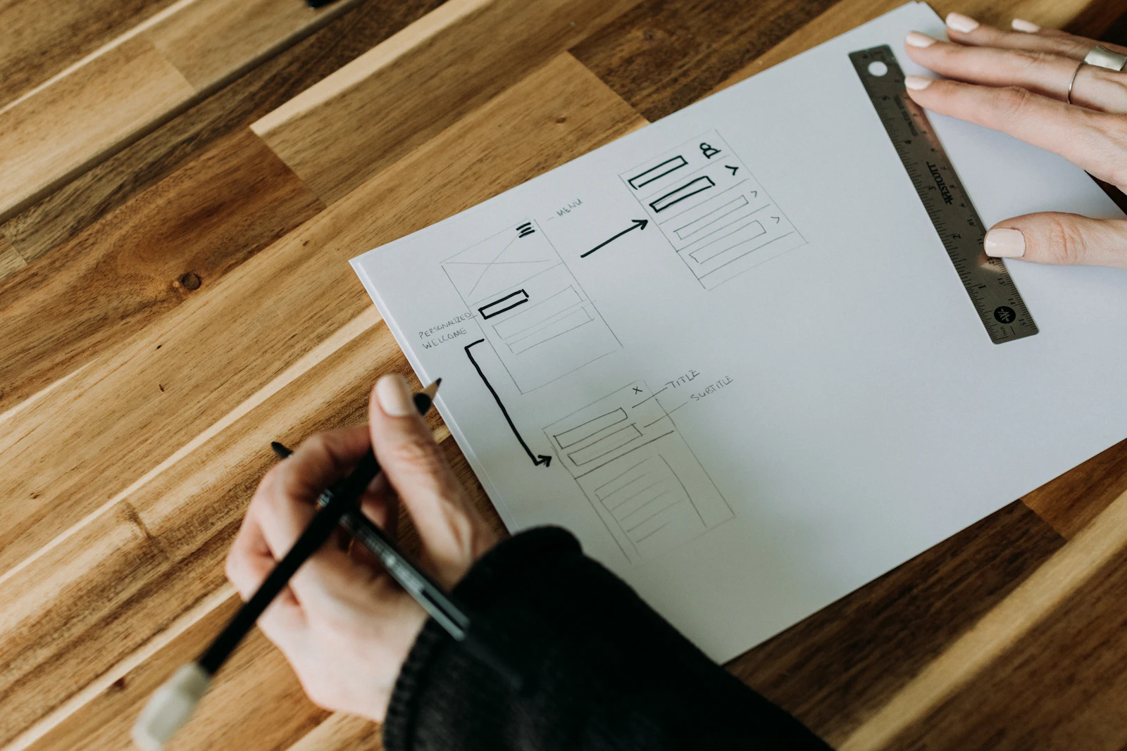 Hands sketching an app interface wireframe on paper