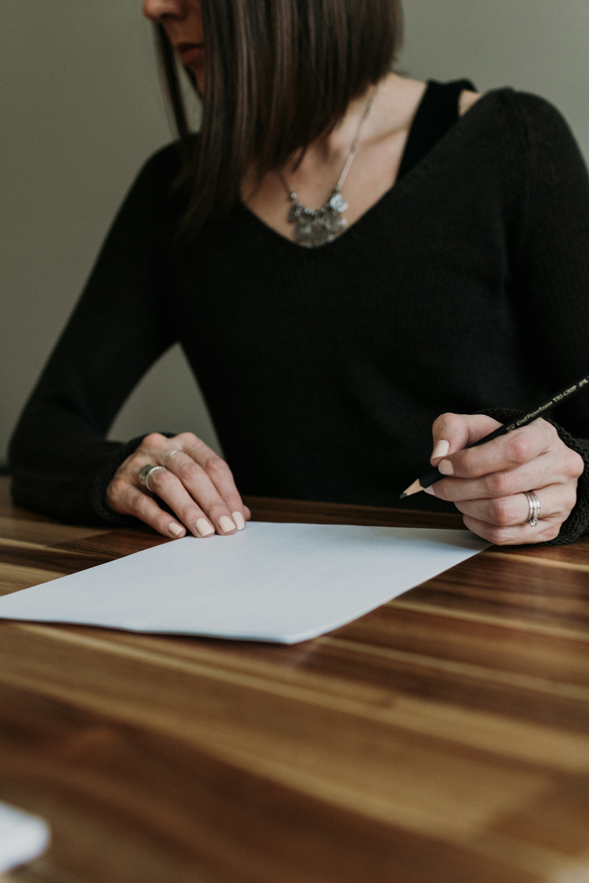 a woman sitting at a table writing on a piece of paper