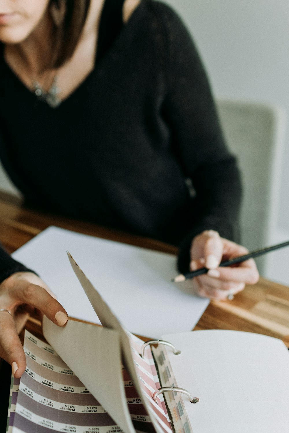 a woman sitting at a table with a binder and pen