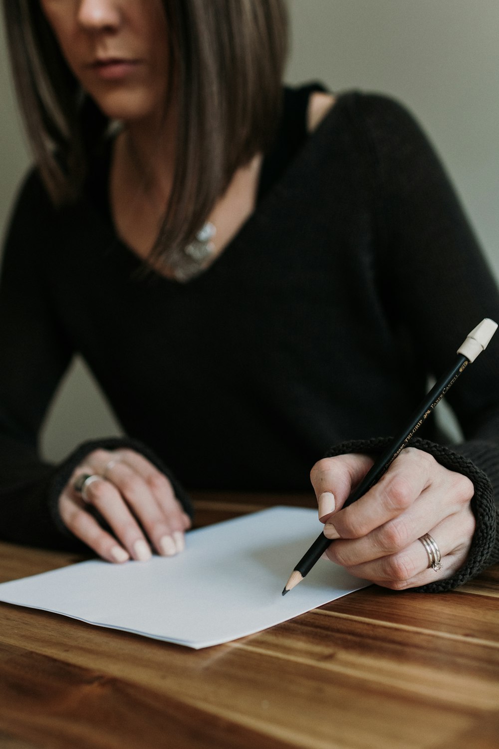 a woman sitting at a table writing on a piece of paper