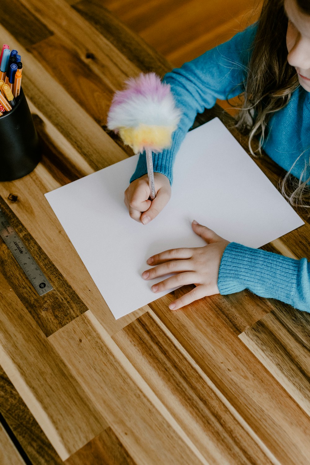 a little girl sitting at a table with a piece of paper and a brush