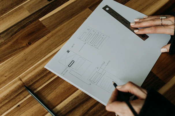 Close-up of a designer sketching a custom metal pin concept on paper.