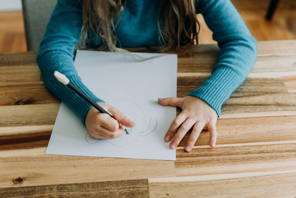 A person sitting at a table with a piece of paper photo – Free School Image  on Unsplash