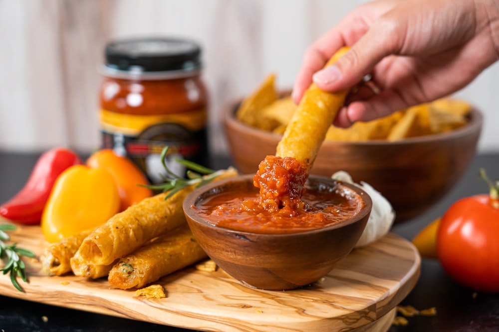 a person dipping some food into a bowl