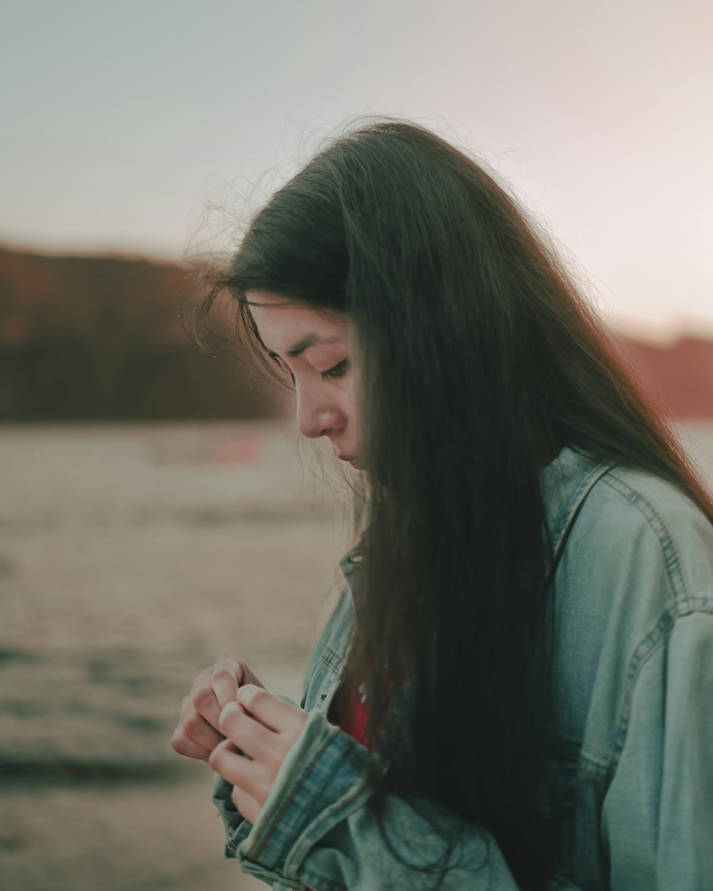 a woman standing on a beach looking at her cell phone