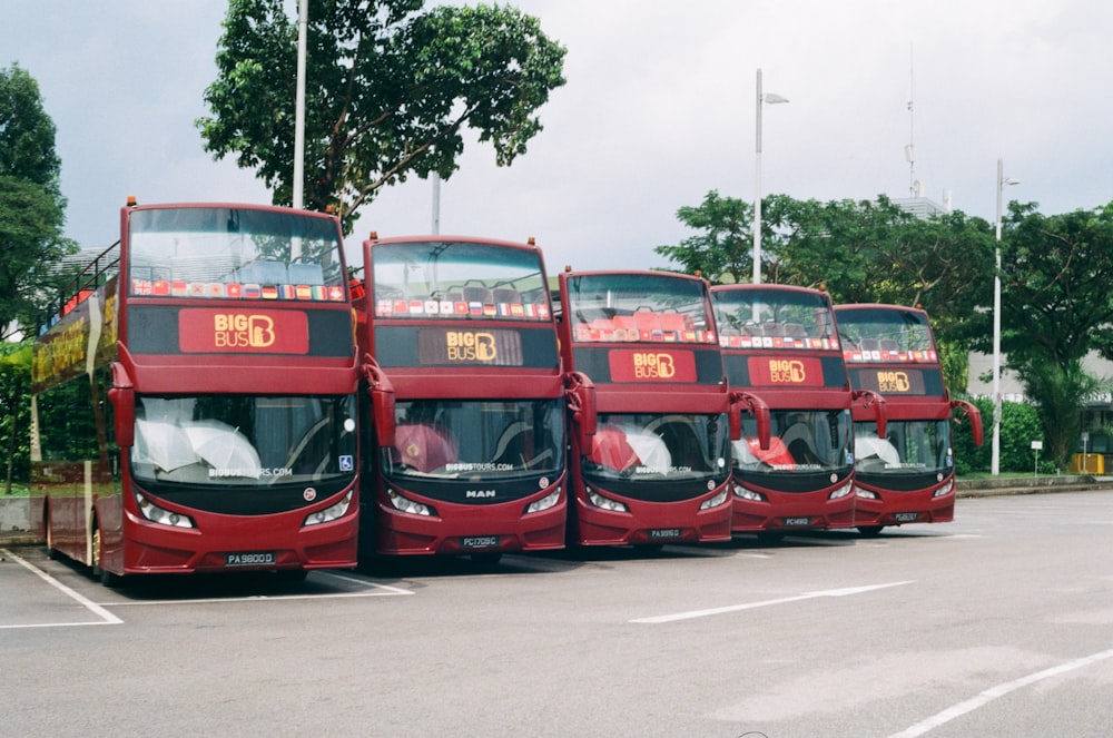 a row of red double decker buses parked next to each other