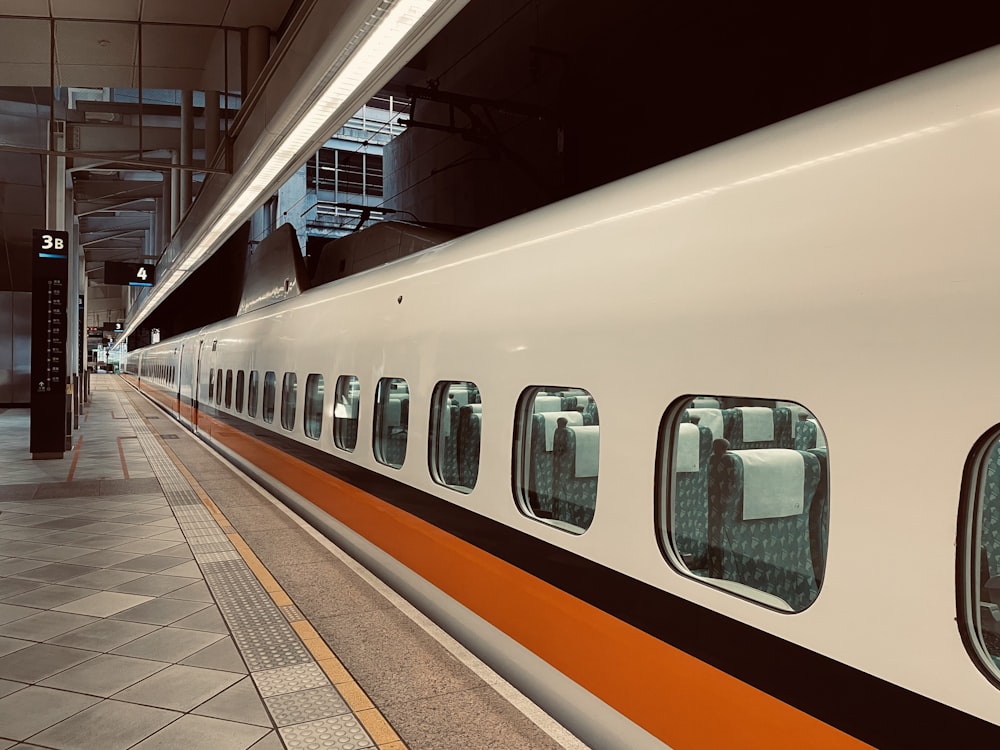 a white and orange train stopped at a train station