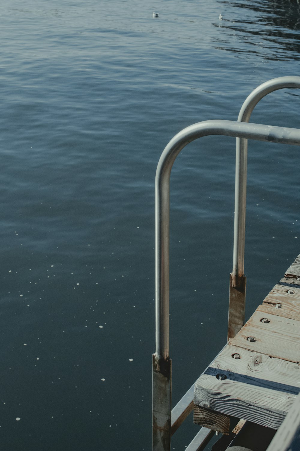 a dock with a metal railing next to a body of water